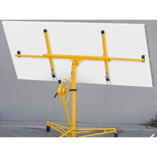 Yellow drywall lift holding a large white panel against a gray wall. The lift is positioned on a concrete floor with wheels at the base.